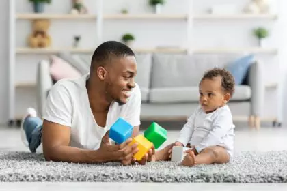 Development Games For Babies. Black Father Playing Stacking Blocks With Infant Child