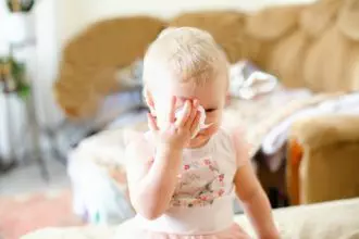 Disease, seasonal virus in a child. Allergy to dust in babies. A girl with the flu wipes her nose