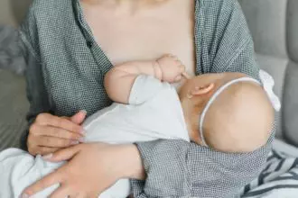 Lactation concept. Young mother breastfeeding her newborn baby at home, close up