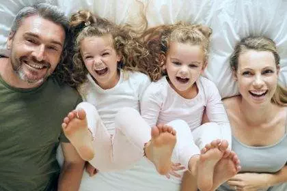 Top view, happy and family with twins in bed smiling together with parents in the morning at home o